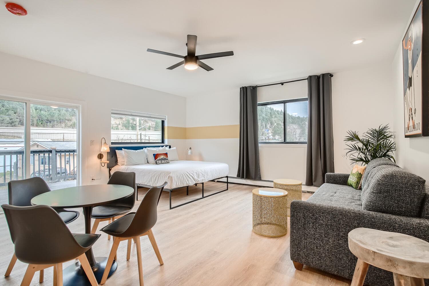 Bright and modern studio with a bed, dining area, and seating, featuring large windows and scenic views.