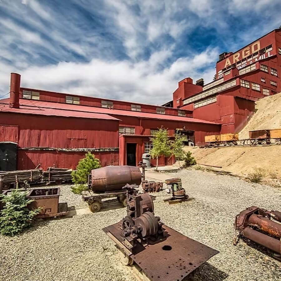 Historic industrial building with rust-colored exterior and surrounding machinery.