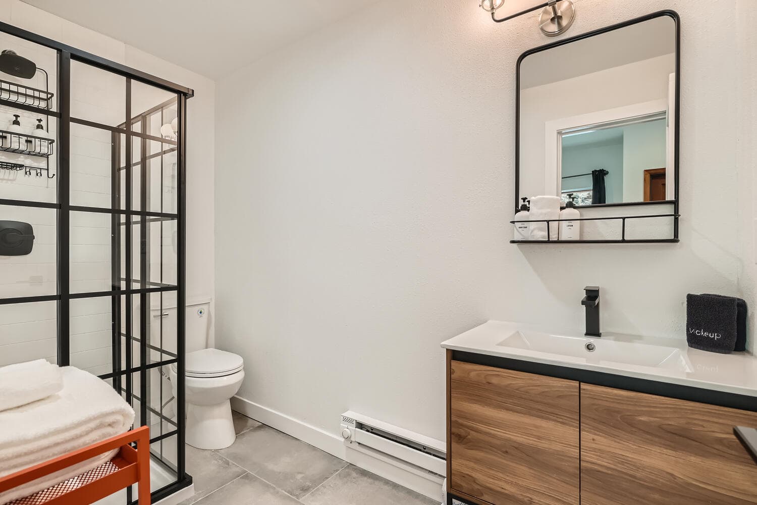 A modern bathroom featuring a glass shower, toilet, and sleek vanity with a mirror.