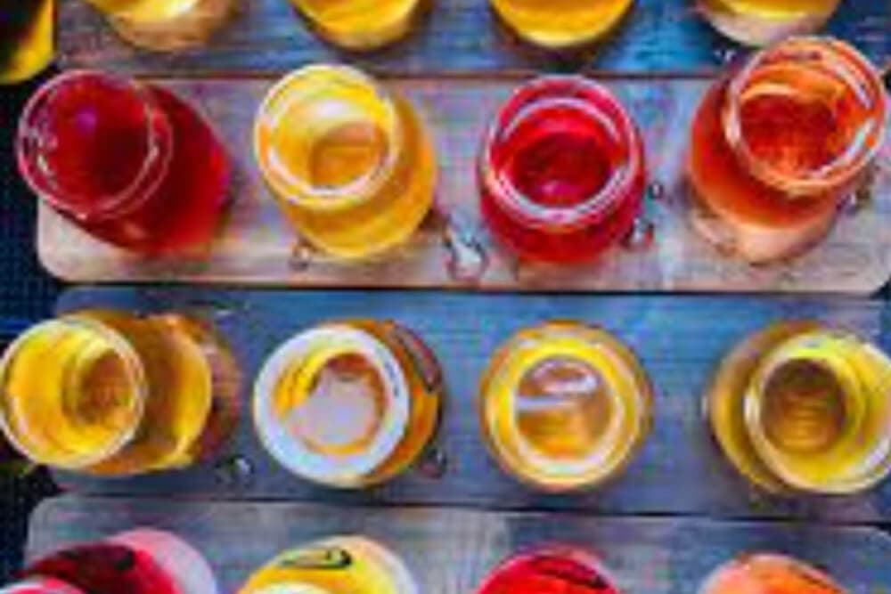 A wooden board holding multiple jars of colorful beverages.