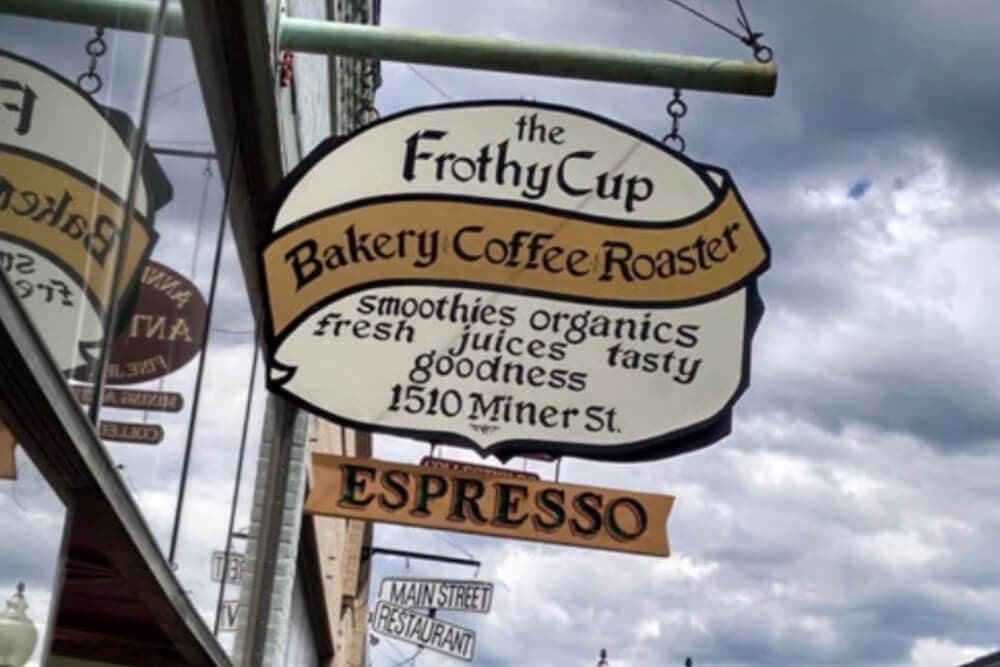 Sign for "The Frothy Cup Bakery Coffee Roaster" featuring espresso and organic offerings.