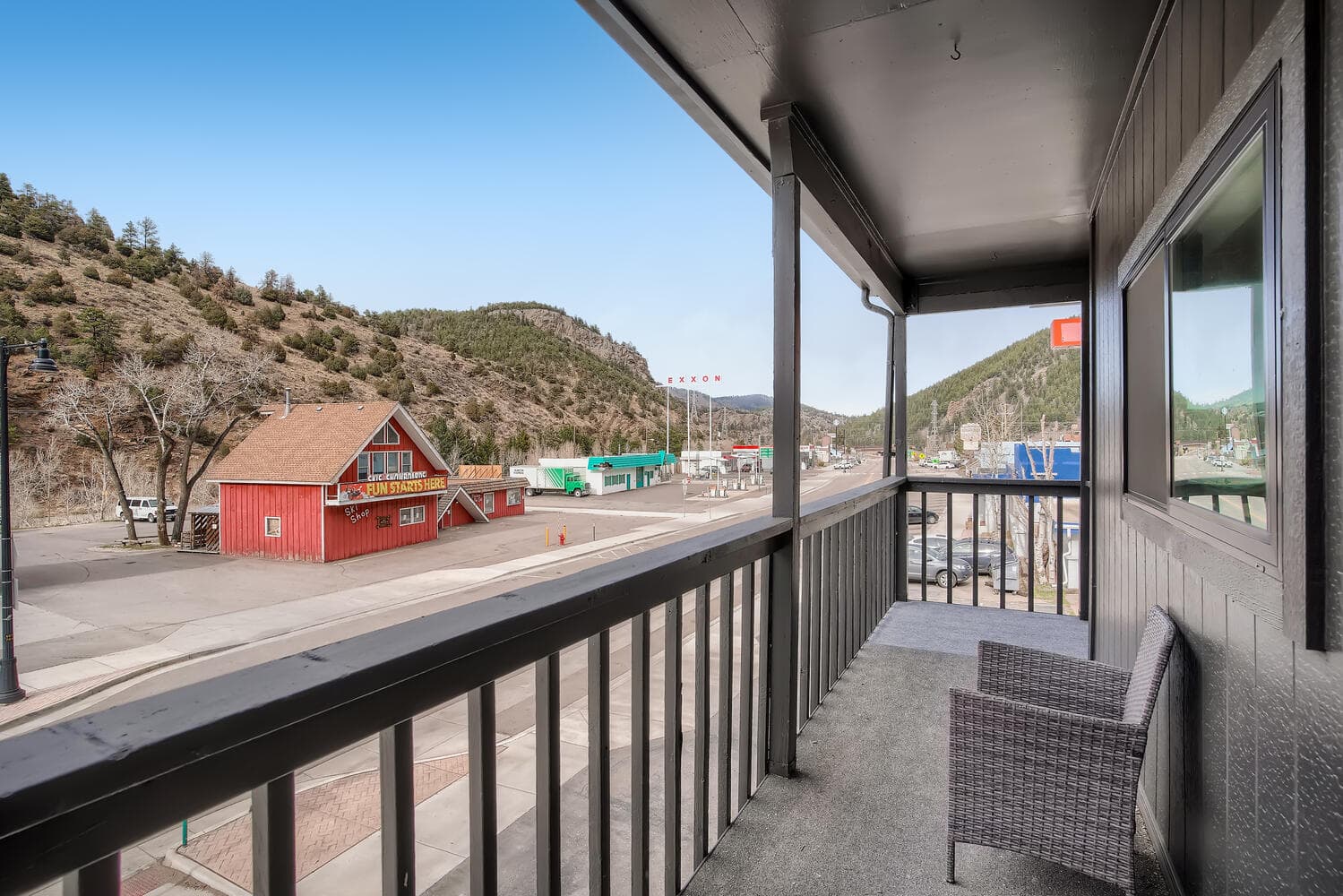 A balcony view overlooking a small mountain town with a few buildings and hills in the background.