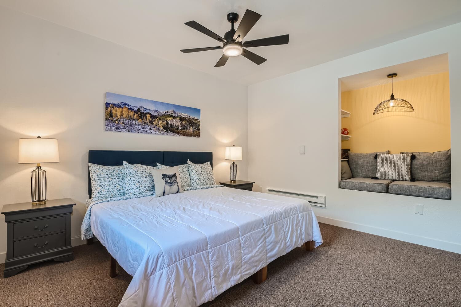 A cozy bedroom featuring a large bed, decorative pillows, and a reading nook with seating.
