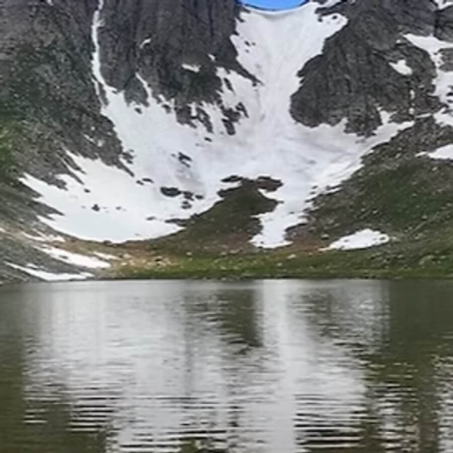 A serene mountain lake reflecting snow-capped peaks under a clear blue sky.