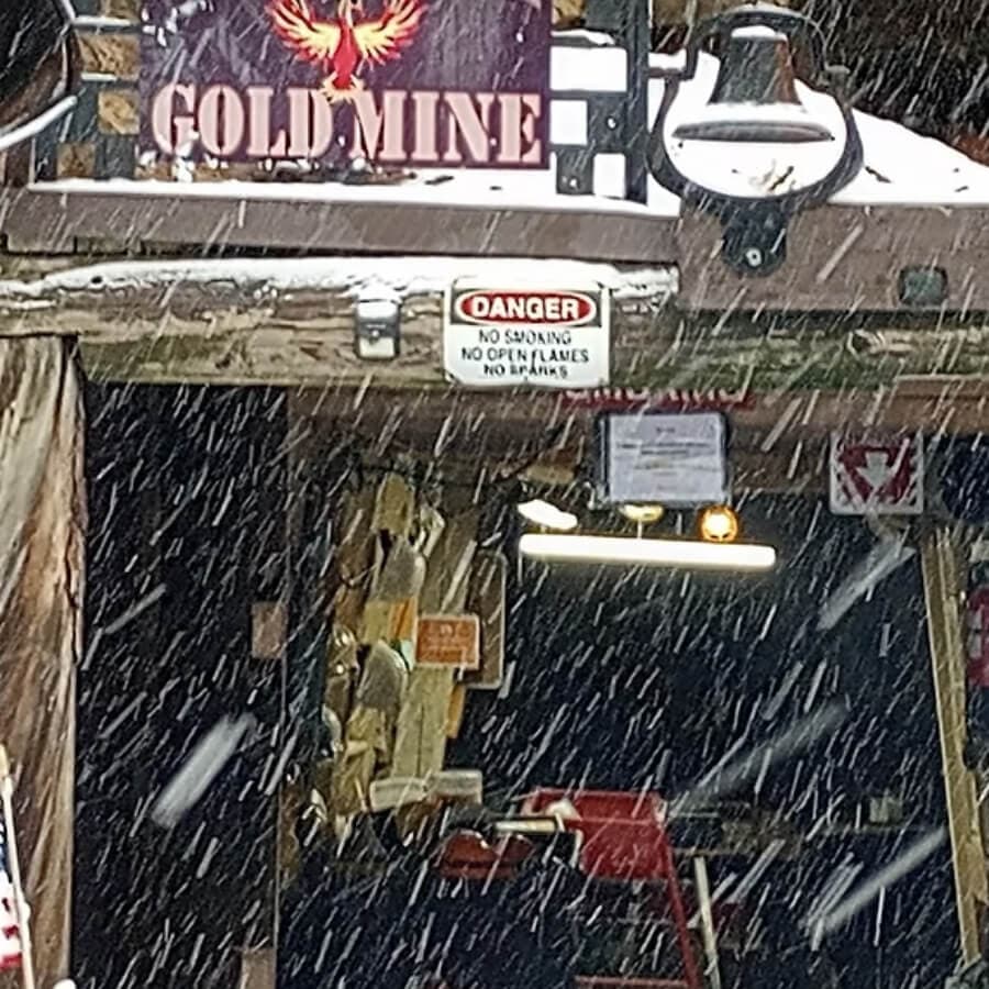 A snow-covered entrance to a gold mine with a "Danger" sign visible.